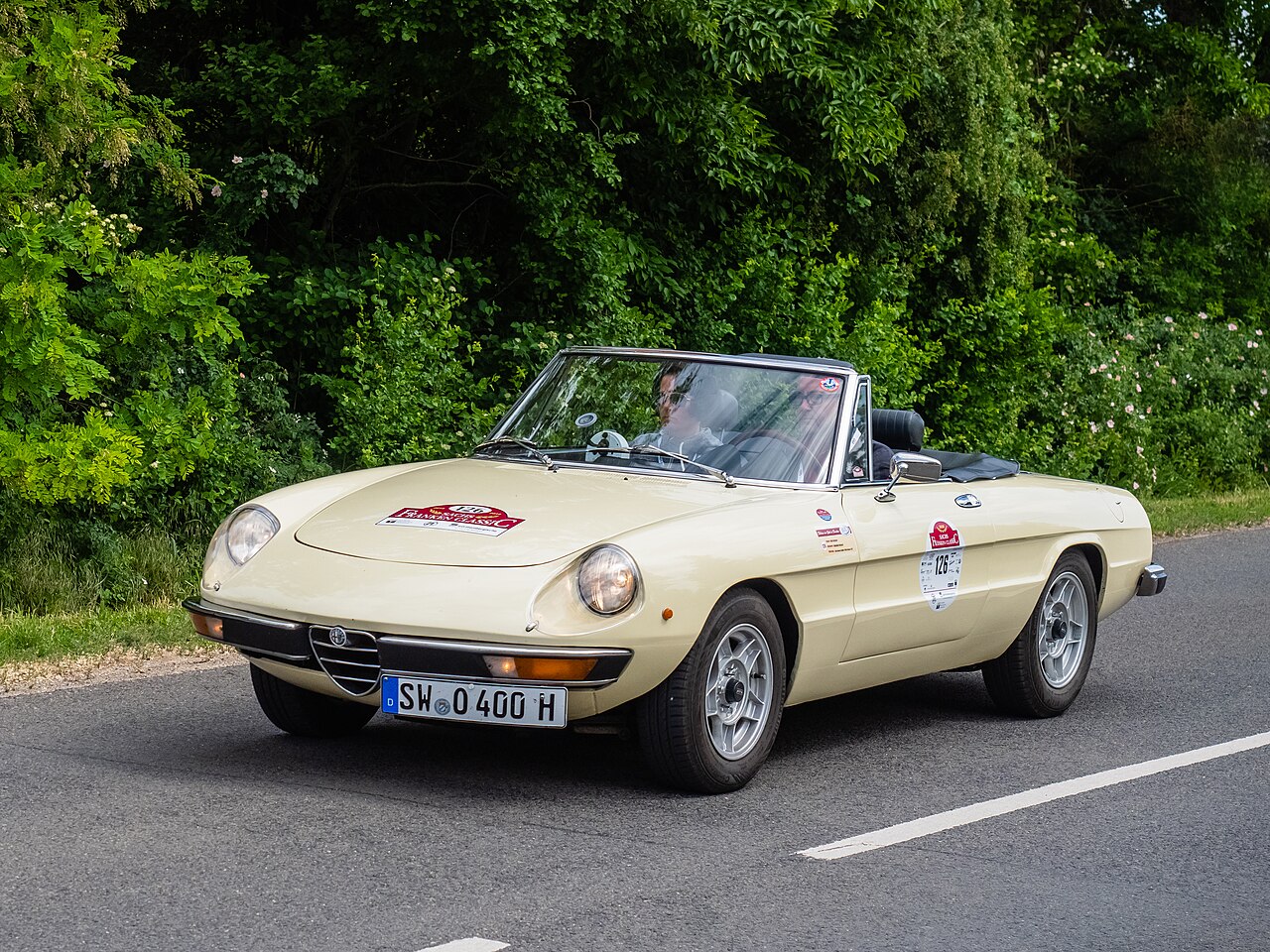 Cream Alfa Romeo Spider 2000 Veloce with its roof down, front left view on a country road during the 2018 Sachs Franken Classic rally.