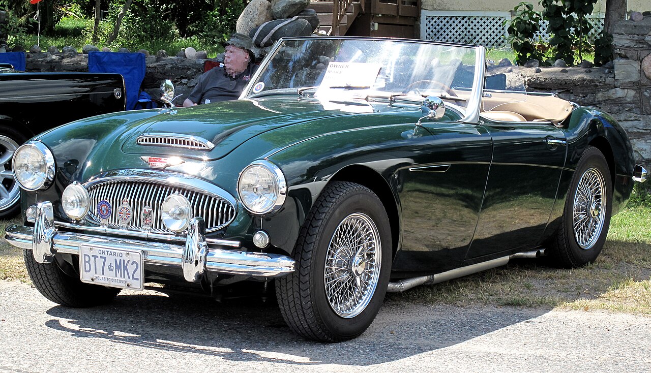 Dark green 1962 Austin-Healey 3000 Mk II with wire wheels and its roof down, front left three-quarter view at a car show.