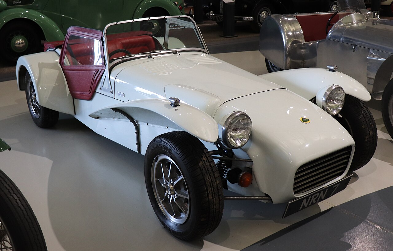 1969 Lotus Seven S3 1.6 in white with maroon trim and an open cockpit, front three-quarter view in a museum.