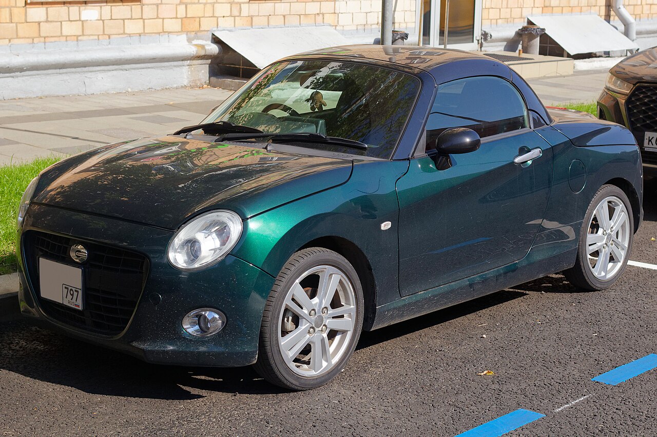 Dark green Daihatsu Copen Cero with its roof up, front left three-quarter view parked on a street in Moscow.