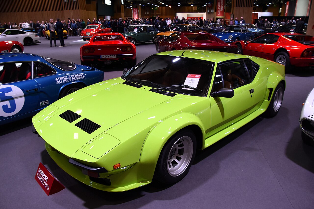 Lime green 1982 De Tomaso Pantera GT5 with wide wheel arches, front left three-quarter view among other classic cars at a show.