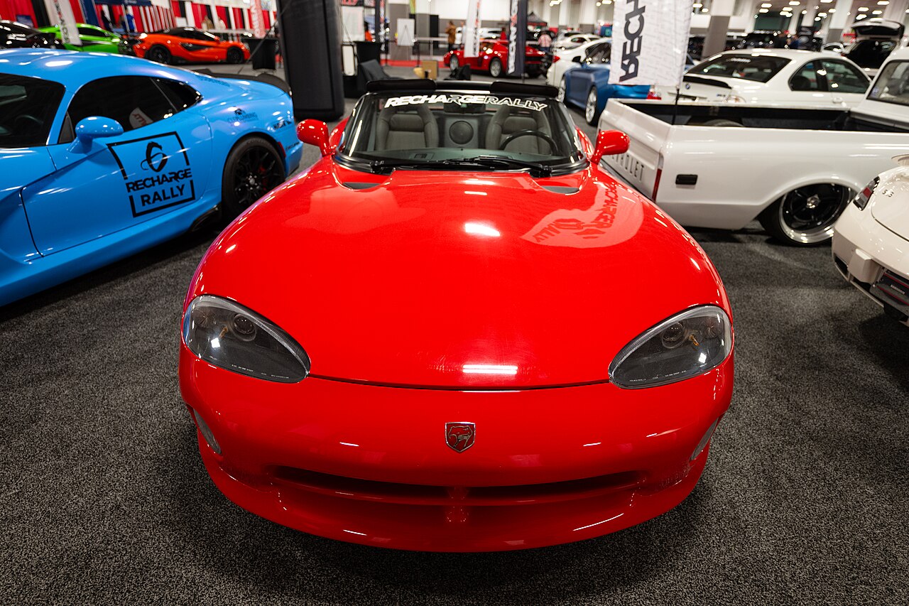Red first-generation Dodge Viper roadster with its roof down, head-on view among other cars at the Cleveland Auto Show.