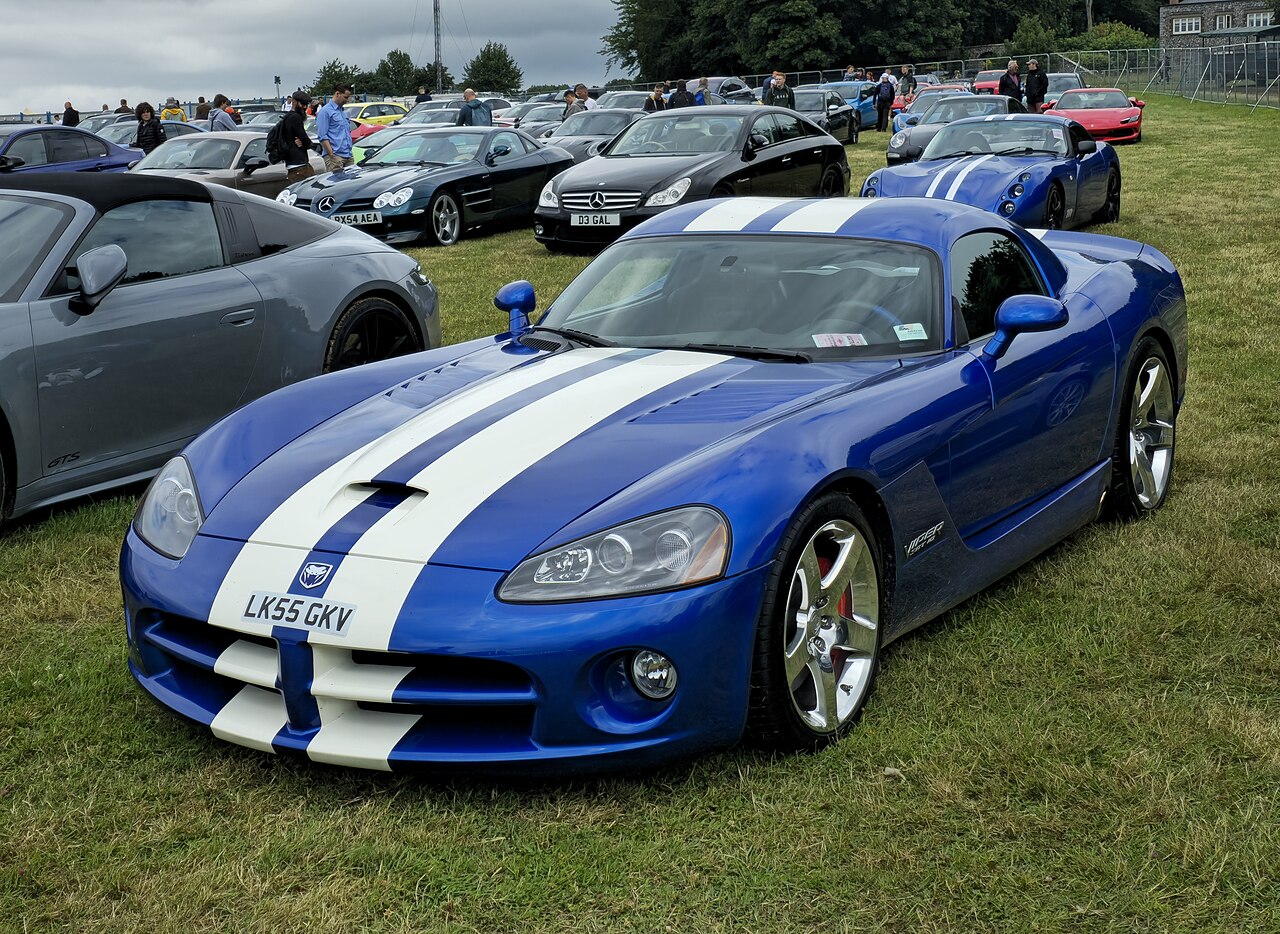 2006 Dodge Viper SRT-10 coupe in blue with white stripes, front left three-quarter view on grass at a car show.
