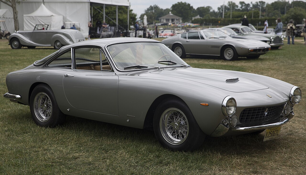 Silver 1963 Ferrari 250 GT Lusso with wire wheels, front right three-quarter view on grass at a concours.