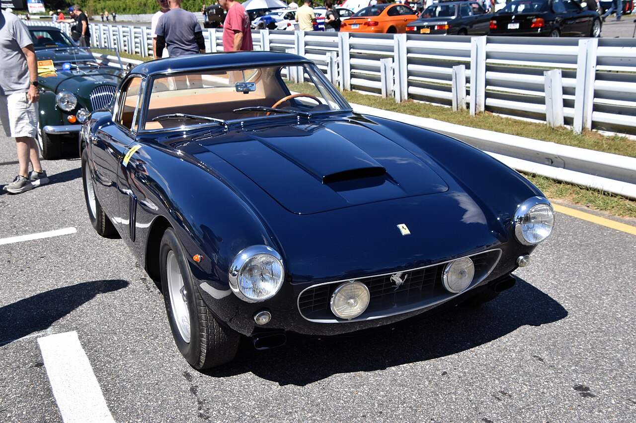 Dark blue 1960 Ferrari 250 GT SWB berlinetta, front three-quarter view at an outdoor car event.