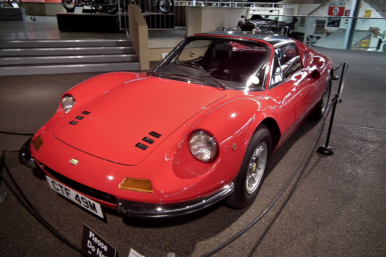 Red 1974 Ferrari Dino 246 GTS with its black targa roof panel fitted, front left three-quarter view in a museum.