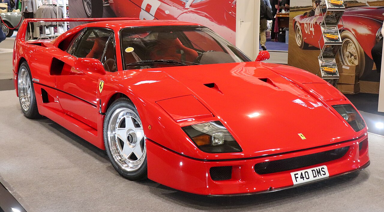 Red 1990 Ferrari F40, front right three-quarter view on the floor of an indoor classic car show.