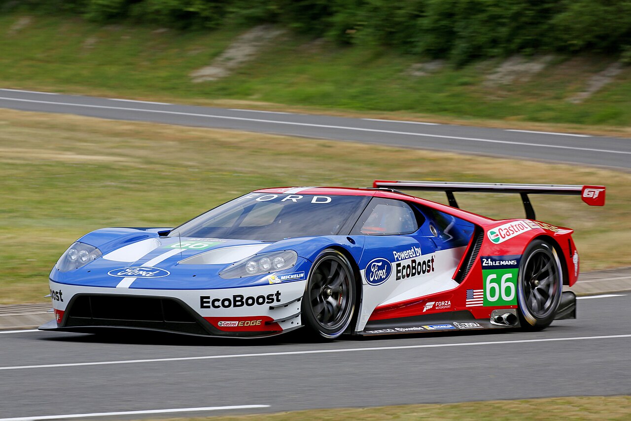 Blue, white and red Ford GT Le Mans GTE race car with the number 66, driving on a circuit in front three-quarter view.