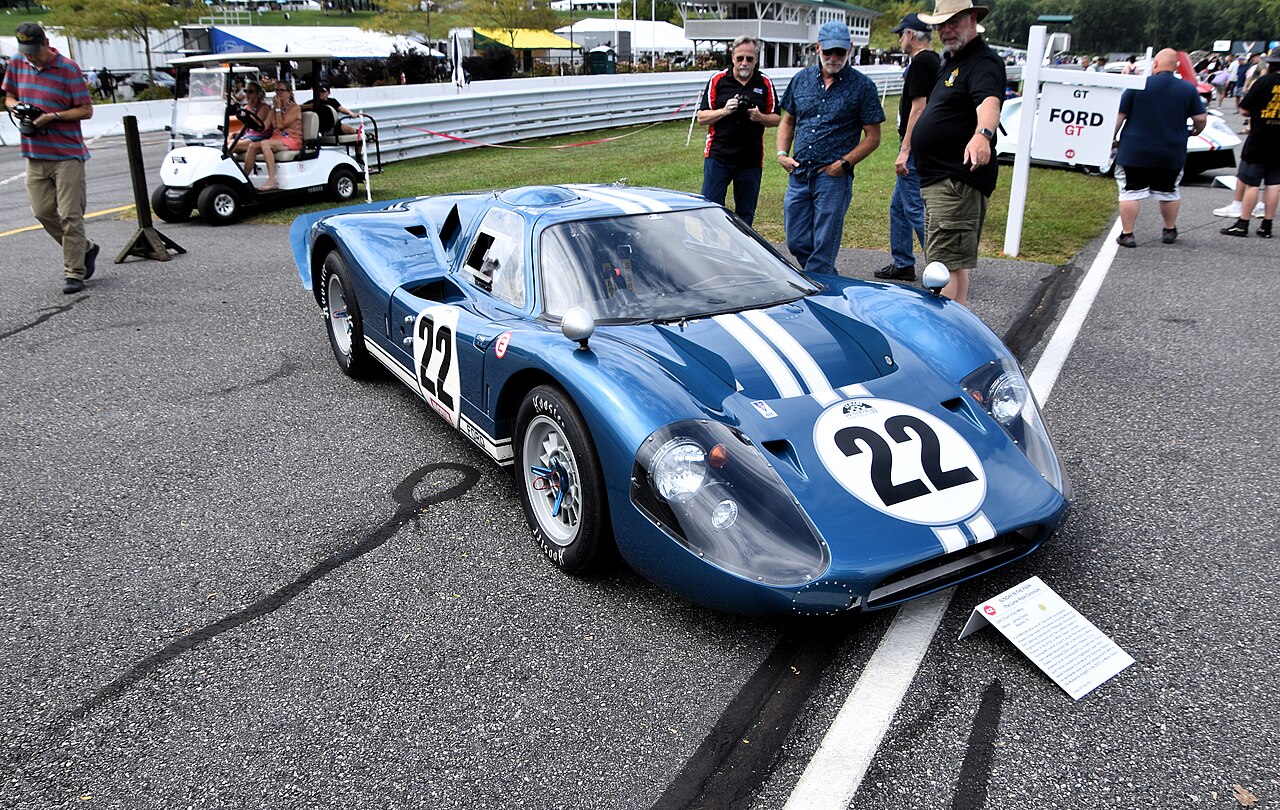 Blue 1967 Ford GT40 Mk IV with white stripes and the number 22, front three-quarter view at a historic racing event.