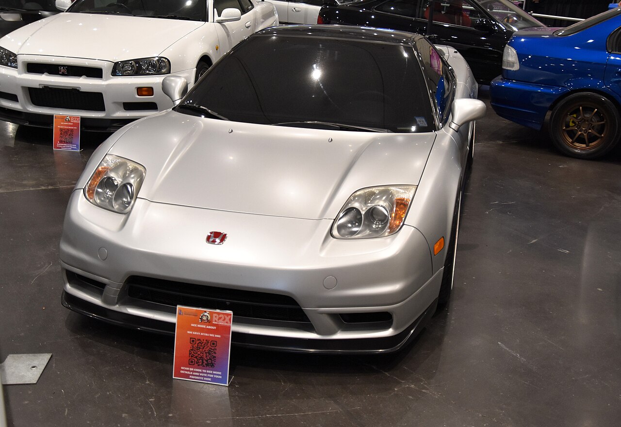 Silver 2005 Acura NSX with fixed headlights, seen from the front at an indoor car show.