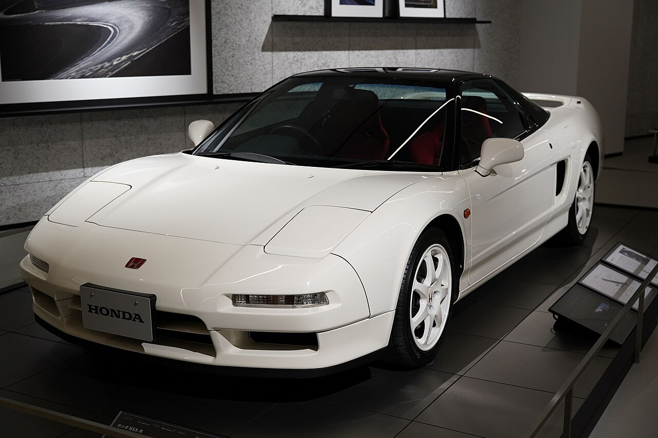 White Honda NSX Type R with white wheels, front three-quarter view in a museum with its pop-up headlights closed.