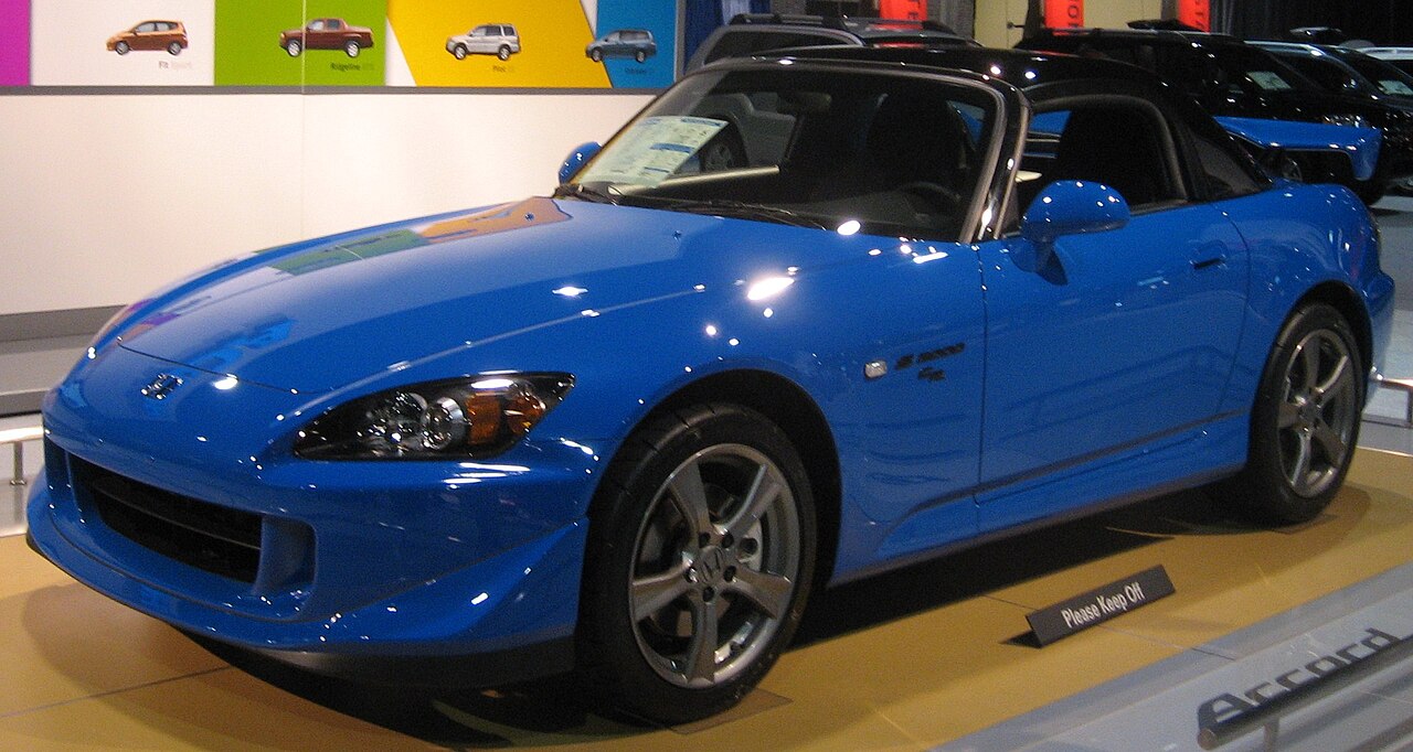 Blue 2008 Honda S2000 CR with its black roof fitted, front three-quarter view on an auto show stand.