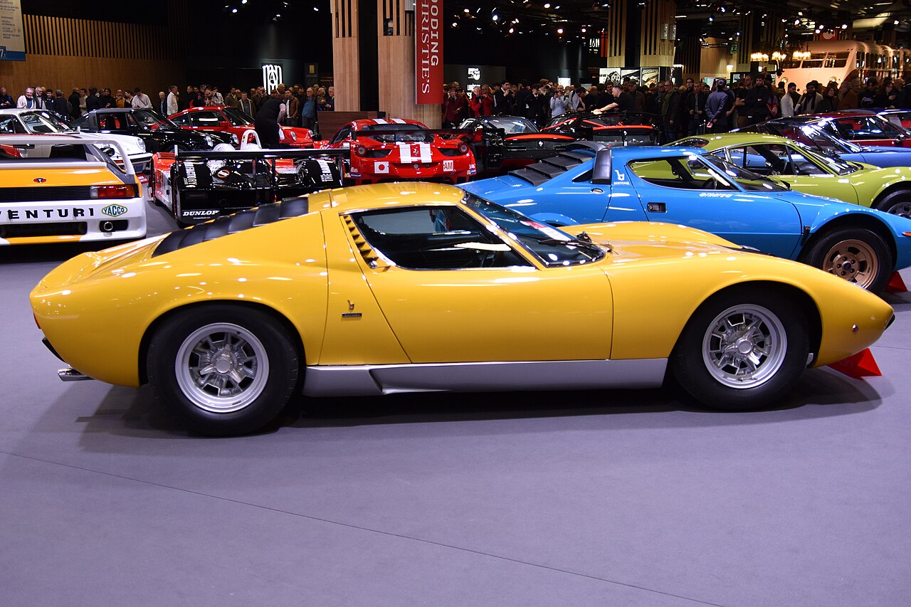 Yellow 1971 Lamborghini Miura P400 SV, side-on view on display at an indoor classic car show.