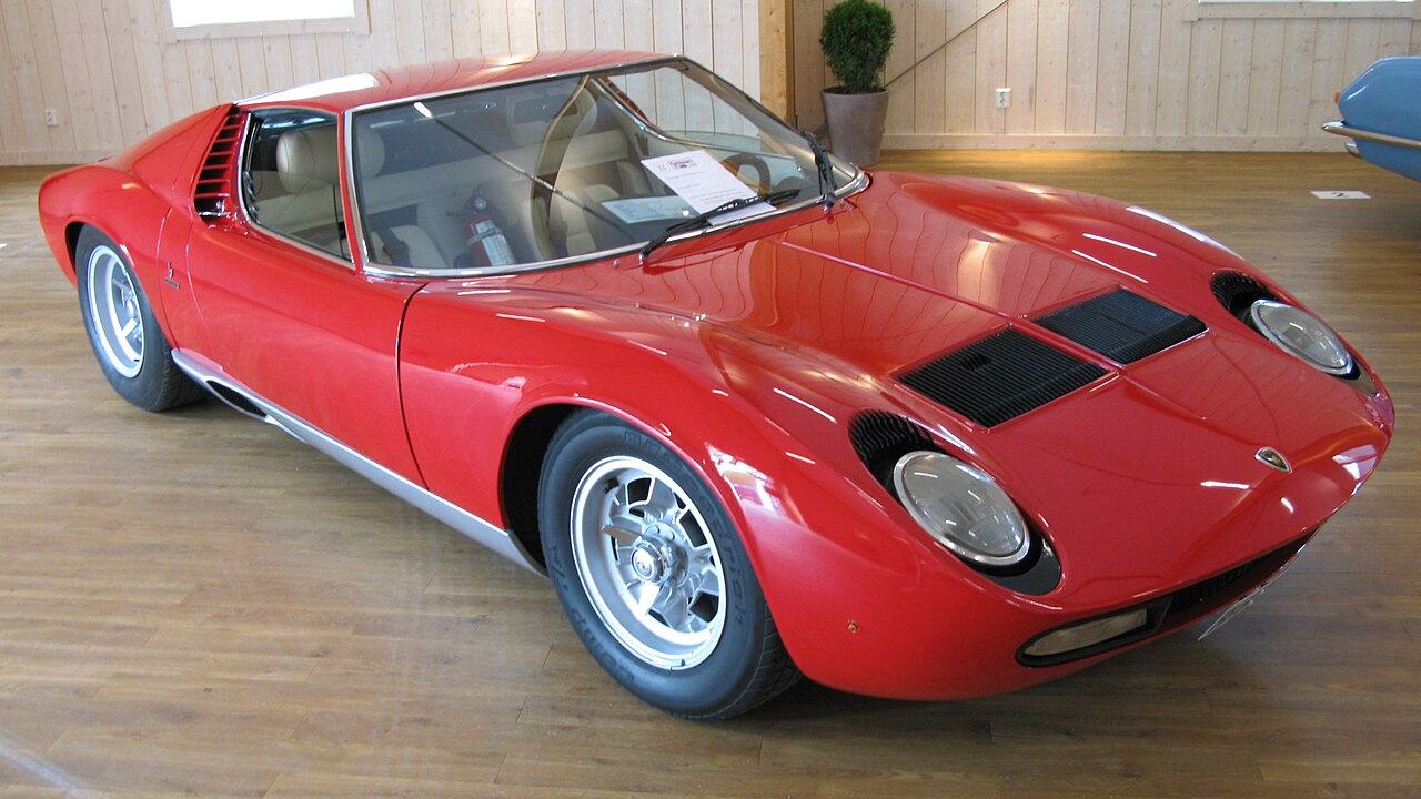 Red 1968 Lamborghini Miura P400, front three-quarter view on a wooden floor indoors.