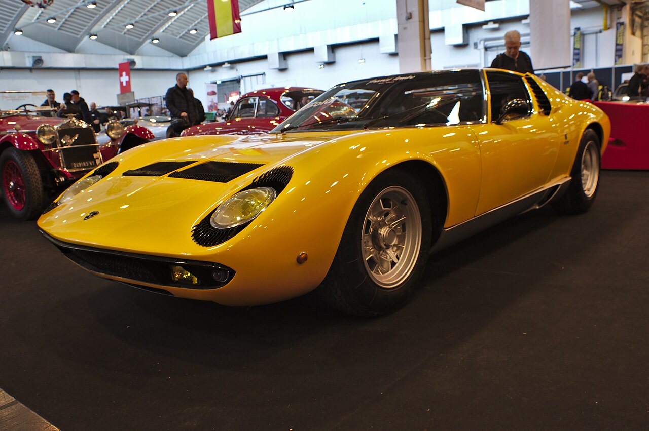 Yellow Lamborghini Miura, front three-quarter view on display at an indoor classic car show.