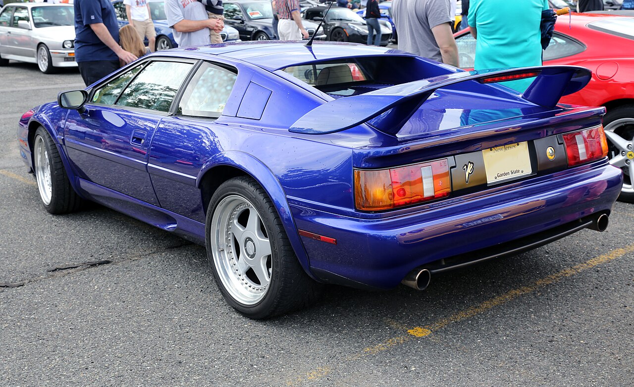1998 Lotus Esprit V8 in purple, rear three-quarter view showing its large rear wing, parked at a car meet.