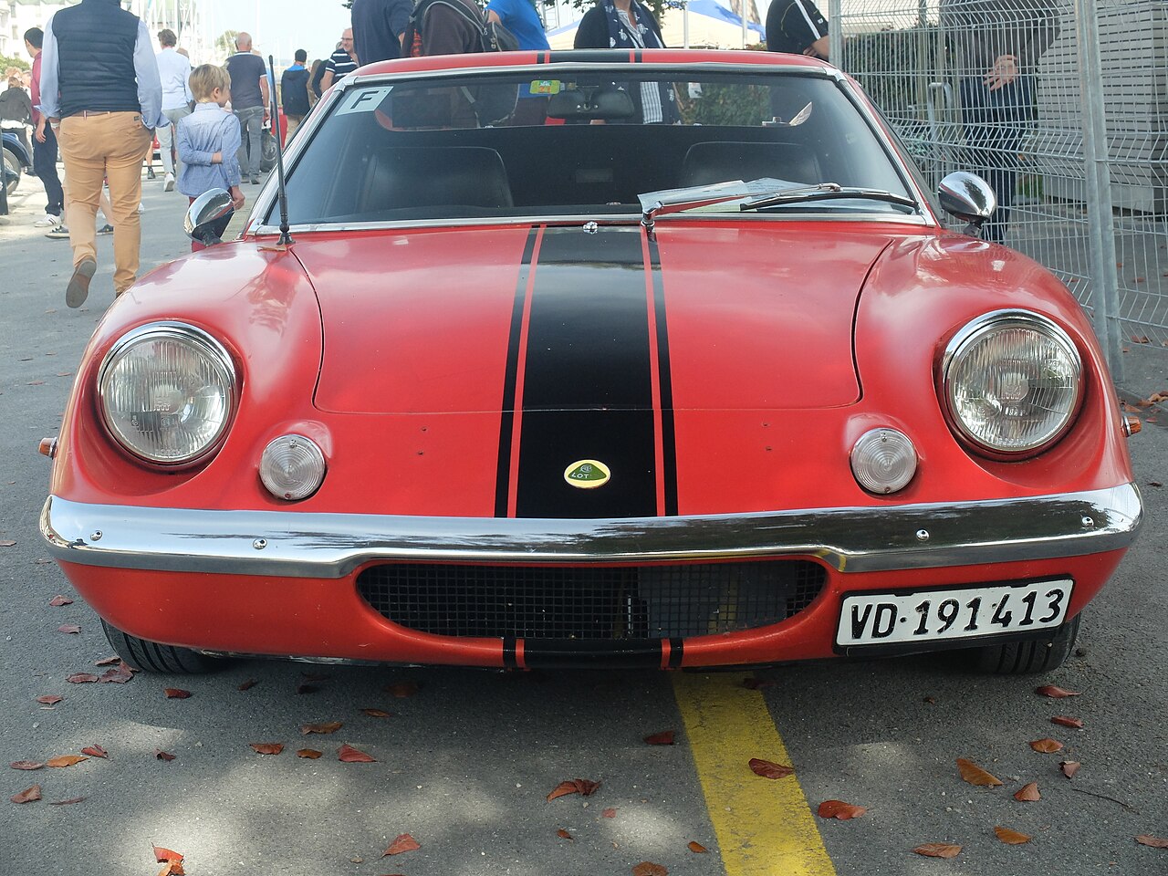 Red Lotus Europa with a black bonnet stripe, seen head-on on a street at a classic British car meeting in Morges.