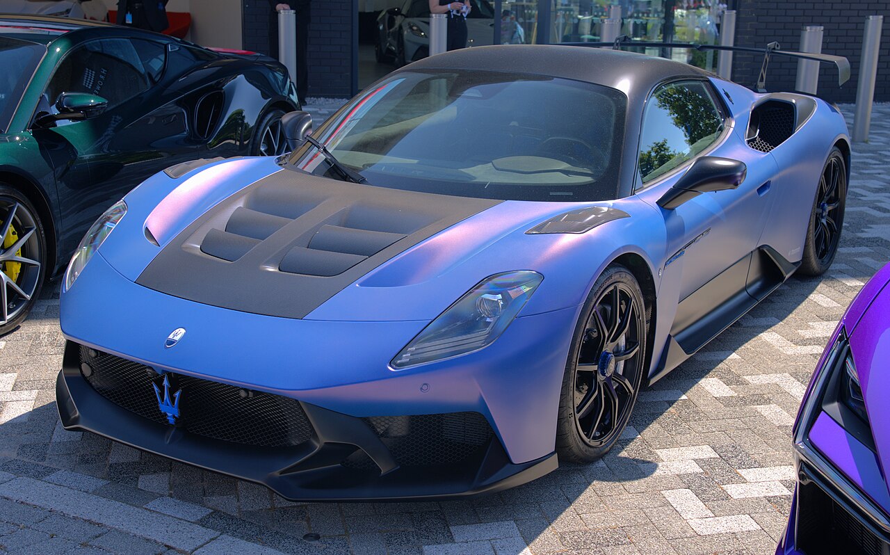 Matte blue Maserati MC20 GT2 Stradale with a carbon bonnet and a large rear wing, seen from the front left on block paving.
