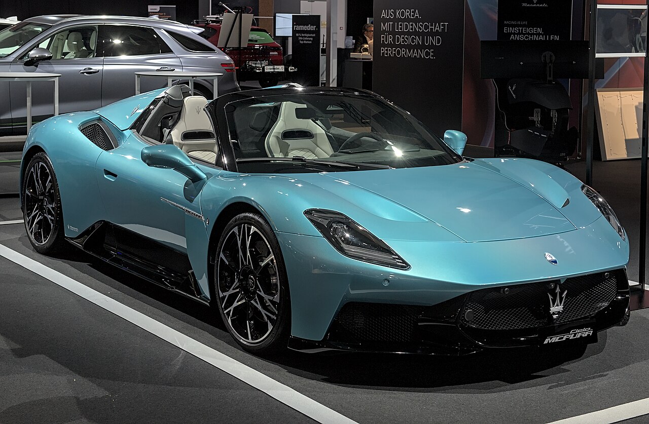 Turquoise Maserati MCPura Cielo with its roof open, front right three-quarter view at an indoor motor show.