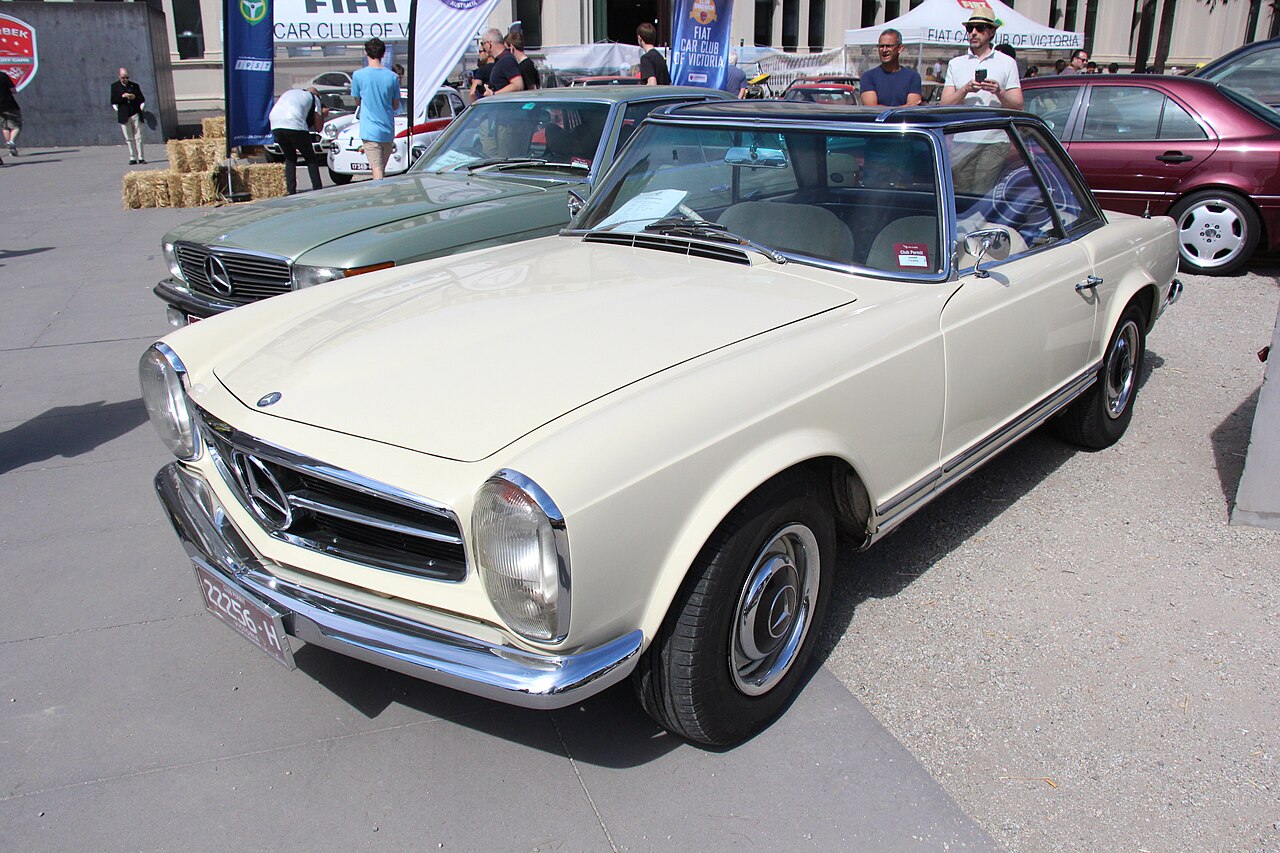Cream 1964 Mercedes-Benz 230 SL Pagoda with a dark hardtop, front left three-quarter view at a classic car show.