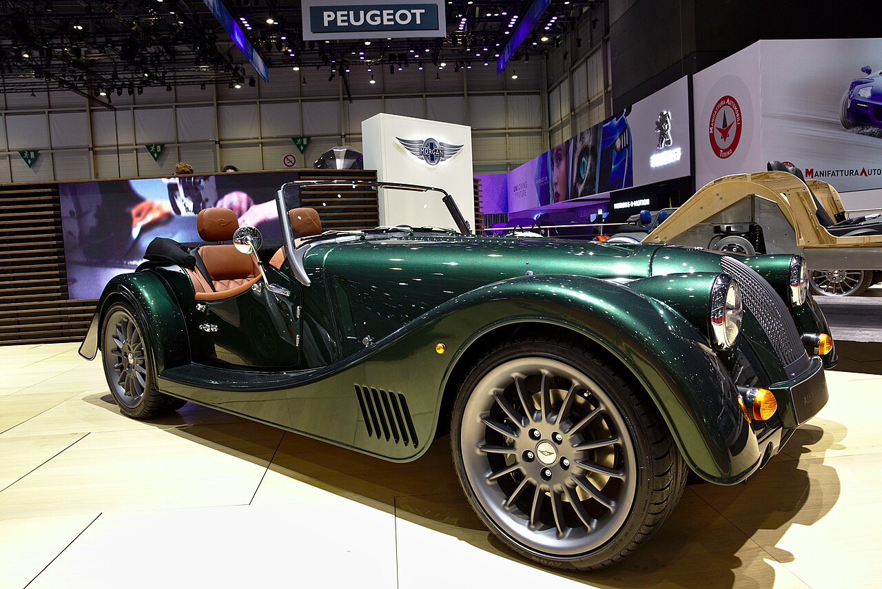 Dark green Morgan Plus Six with tan leather seats and its roof down, front three-quarter view at the 2019 Geneva Motor Show.