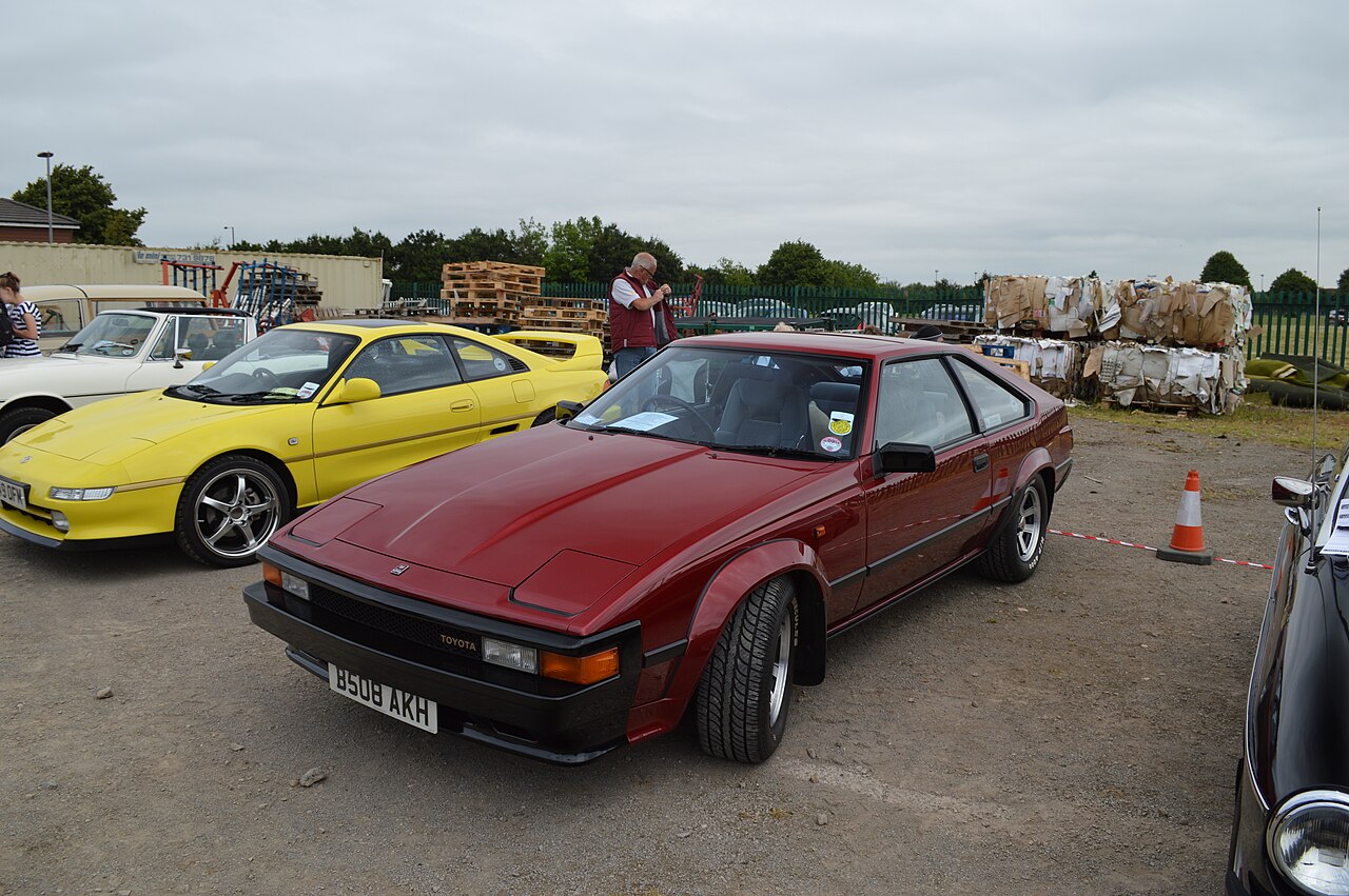 Dark red Toyota Celica Supra, front left three-quarter view on gravel at a classic car show.