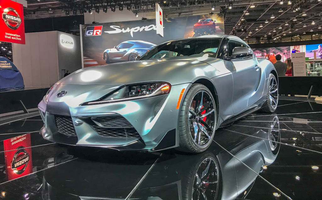 Silver-grey Toyota GR Supra on a display stand, front left three-quarter view at the 2019 Detroit Auto Show.