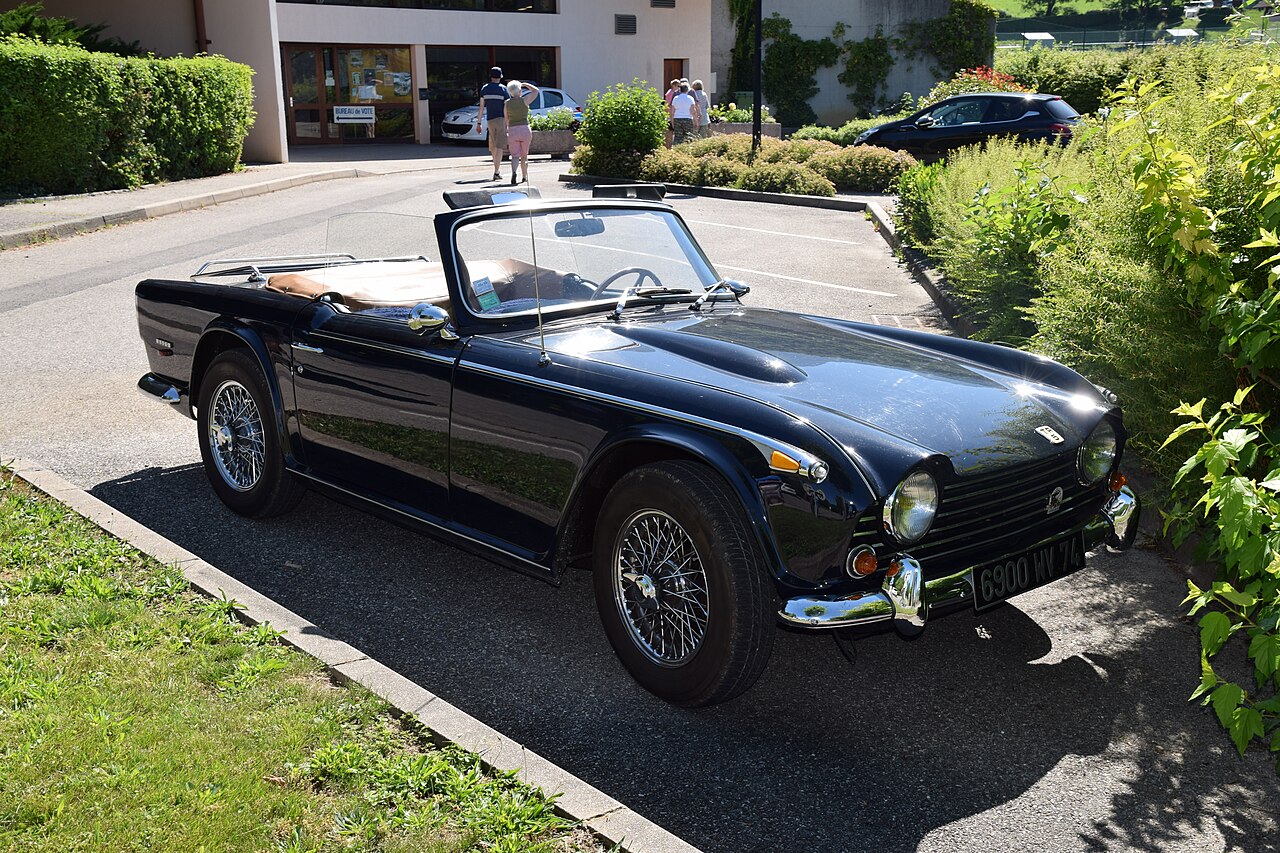 Dark blue 1968 Triumph TR5 roadster with wire wheels and its roof down, front three-quarter view in a car park.
